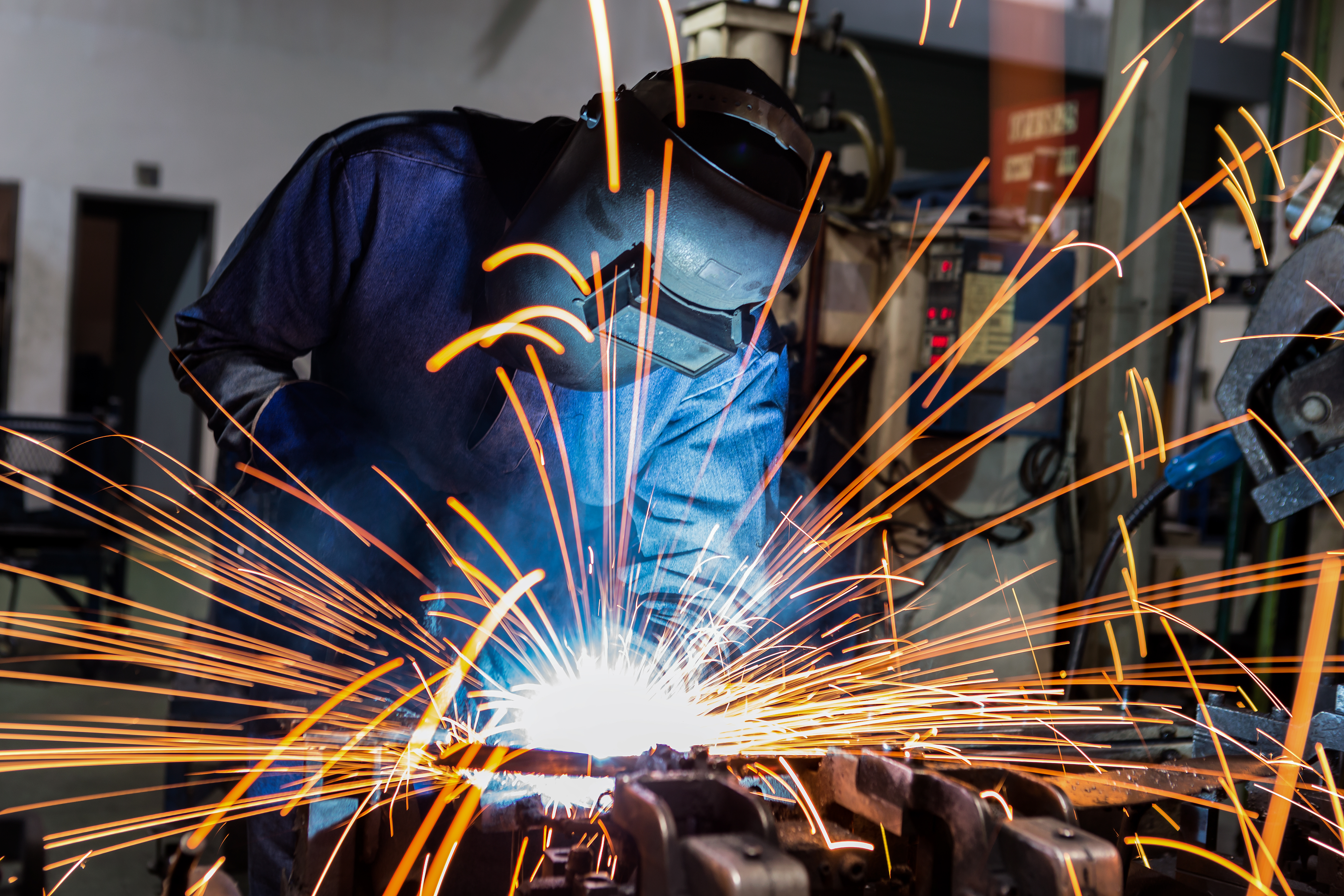 Worker With Protective Mask Welding Metal And Sparks